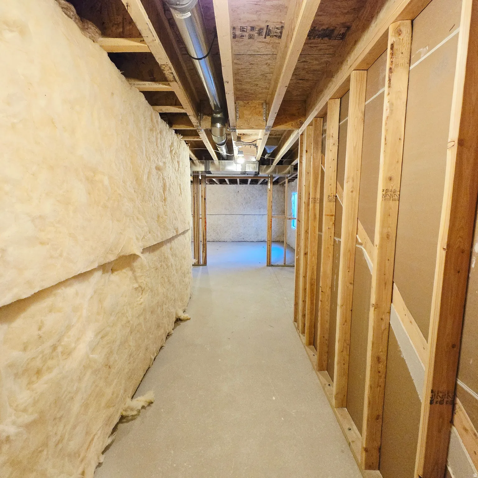 Unfinished basement space featuring exposed wood framing, ceiling joists, and concrete flooring