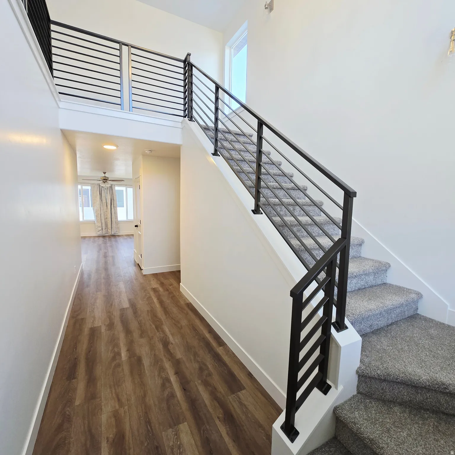 Modern interior staircase featuring black metal railings and light gray carpeted steps