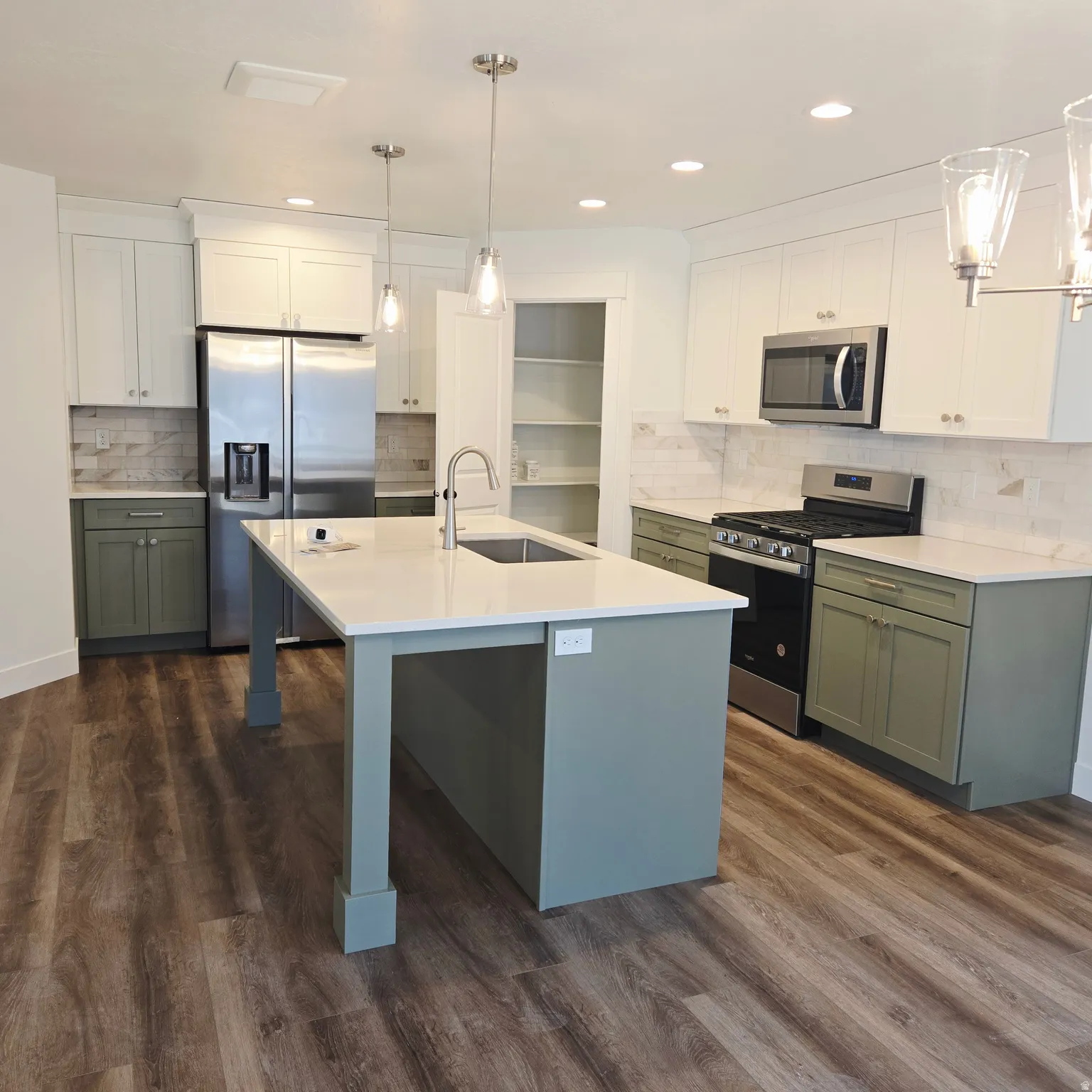 Kitchen featuring a large central island with an undermount sink, quartz countertops, and stainless steel appliances