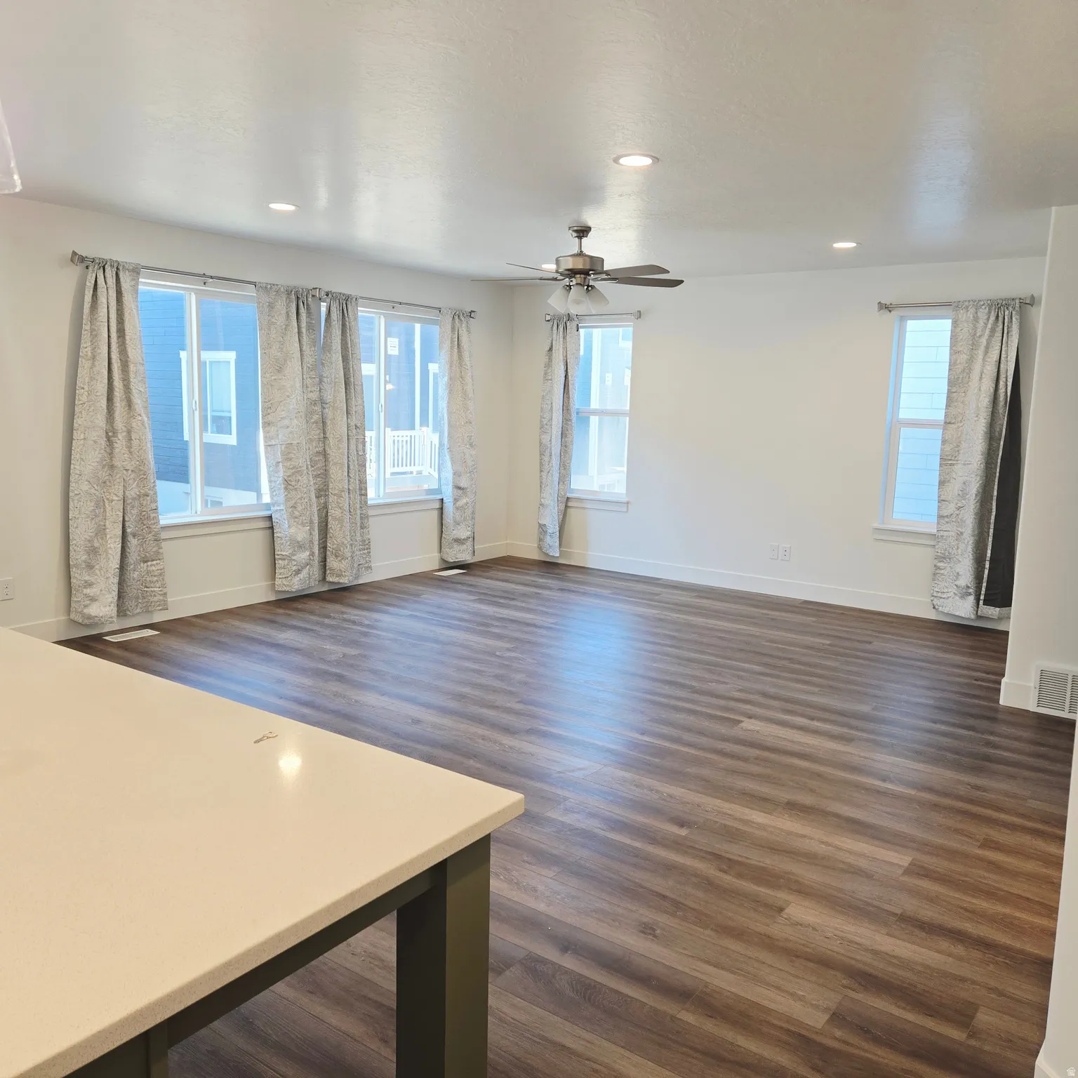 Spacious living area featuring wood-finish flooring, recessed lighting, and a ceiling fan
