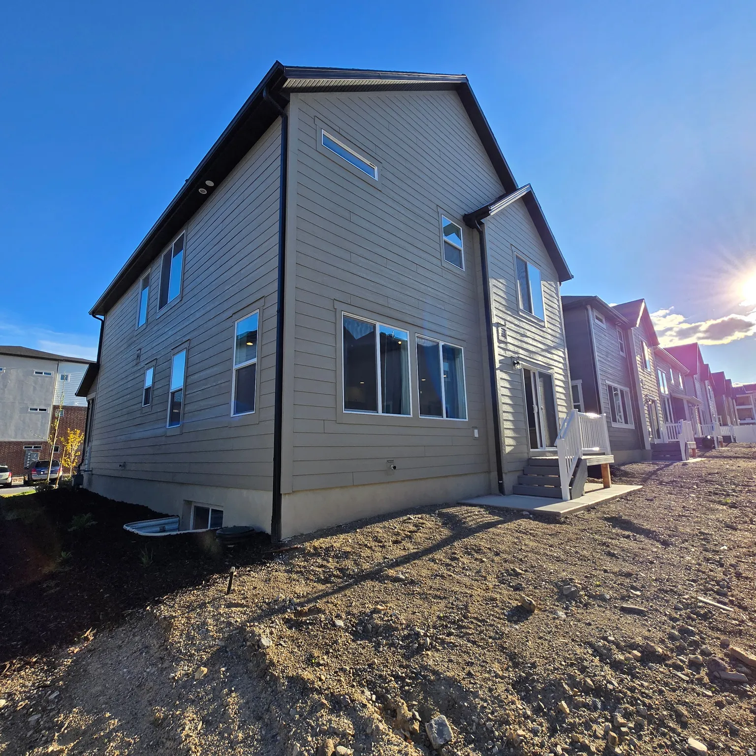 Rear exterior of a two-story residence featuring horizontal siding, multiple windows, and a sliding glass door