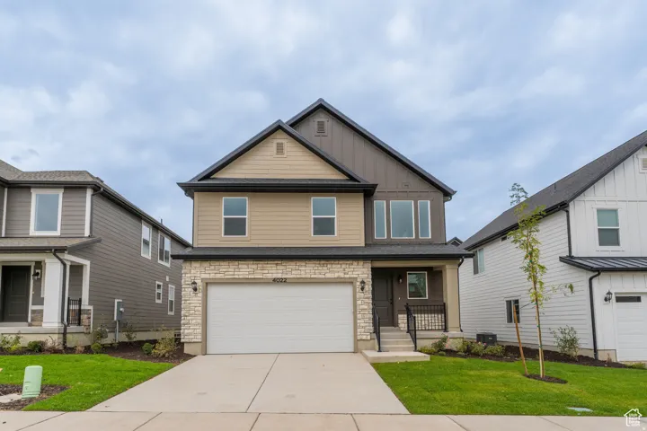 Modern two-story residence featuring a two-car garage, stone veneer siding, and a covered entryway