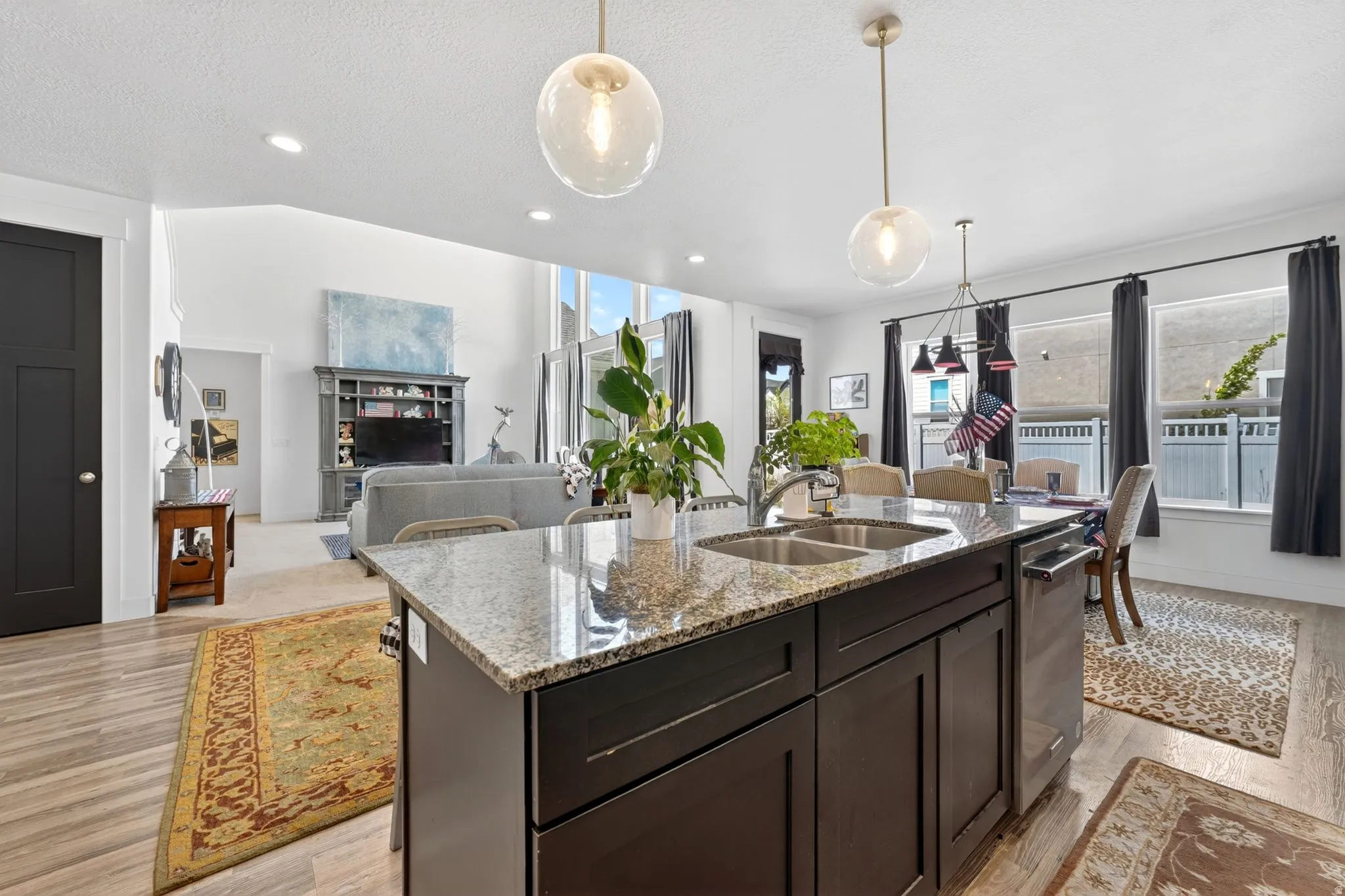 Kitchen island featuring granite countertops, a double basin sink, and integrated dishwasher
