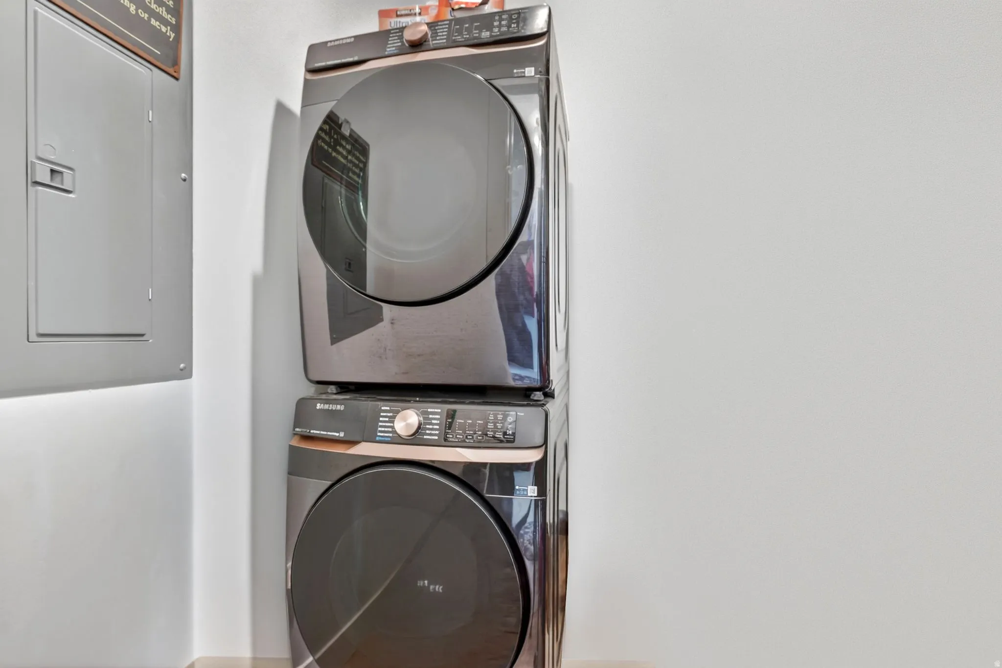 Stackable washer and dryer unit featuring a dark finish and bronze accents