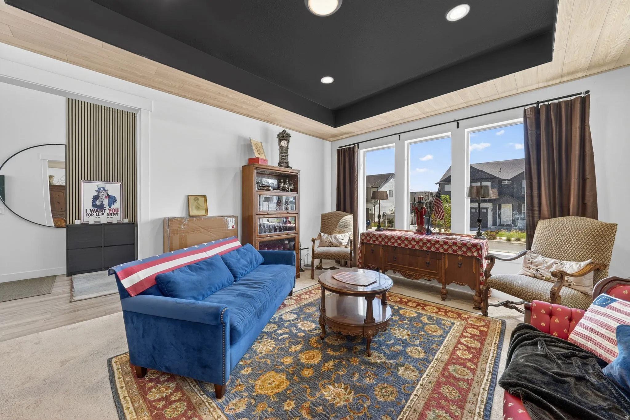 Spacious room featuring a dark tray ceiling with wood-finish accents, large windows, recessed lighting, and light wood-finish flooring