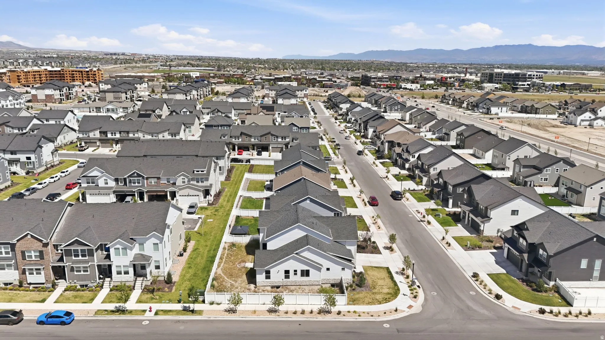 Expansive residential development featuring various architectural styles, paved streets, manicured landscaping, and mountain ranges in the distance