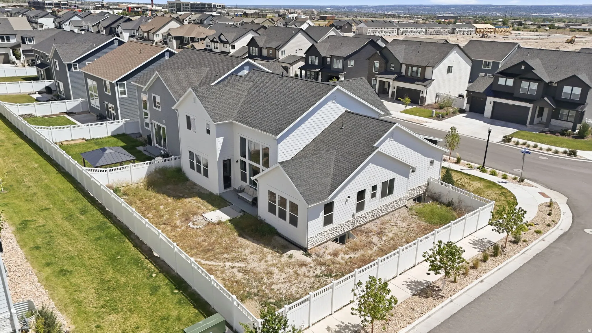 Contemporary residence featuring a white exterior with dark roof, stone accents, and large windows