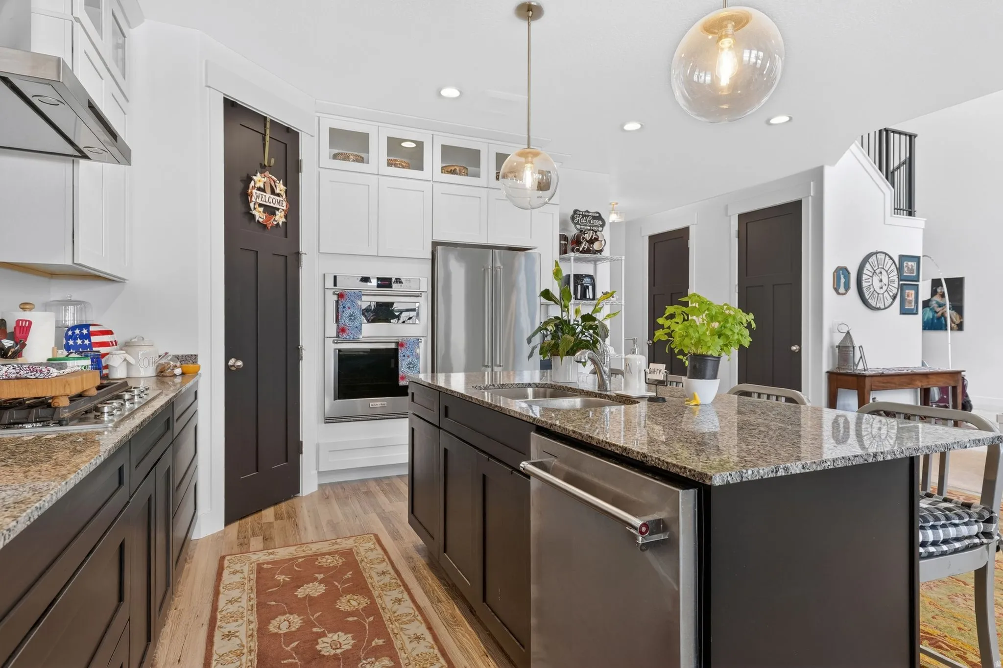 Well-appointed kitchen featuring a large island with a stainless steel dishwasher, granite countertops, and wood-finish flooring