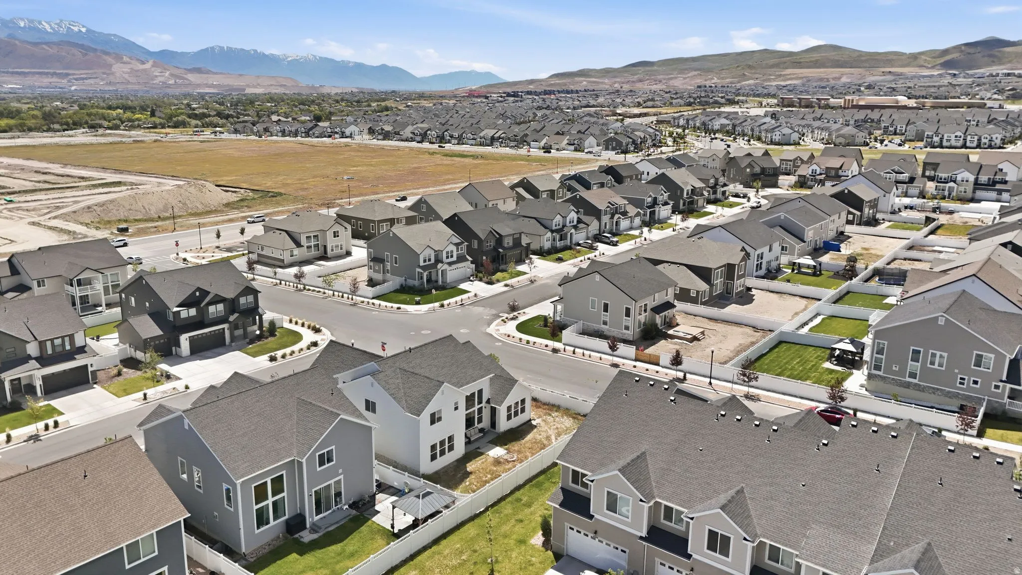 Aerial depiction of a residential development featuring varied house styles, mature landscaping, and mountainous backdrops