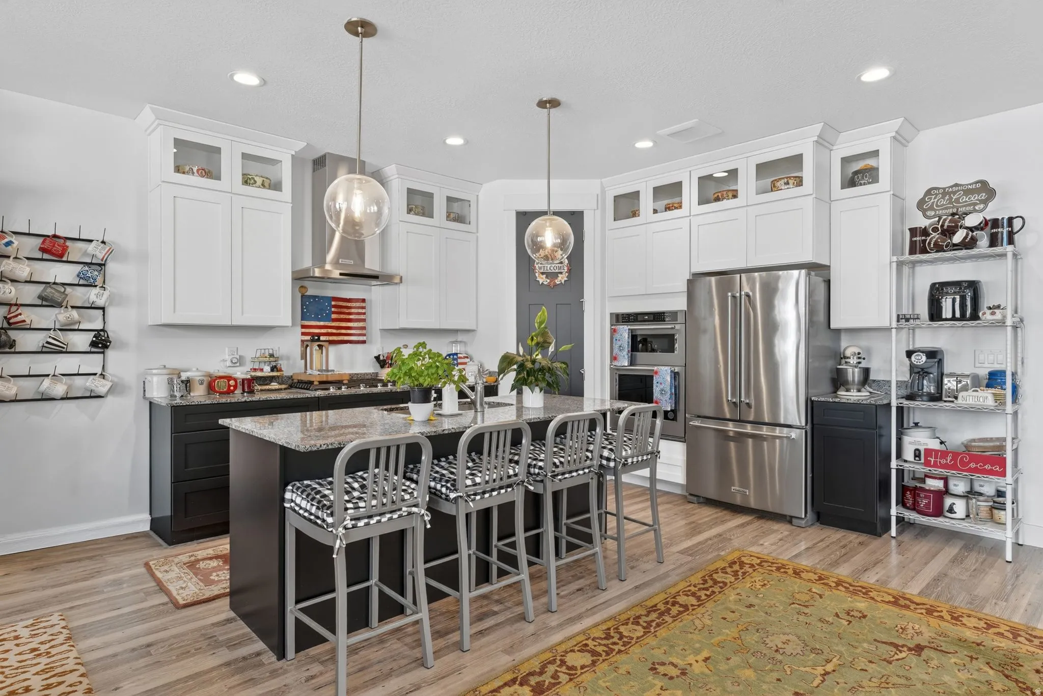 Spacious kitchen featuring an expansive center island with seating, stainless steel appliances, white upper cabinetry, and dark lower cabinetry
