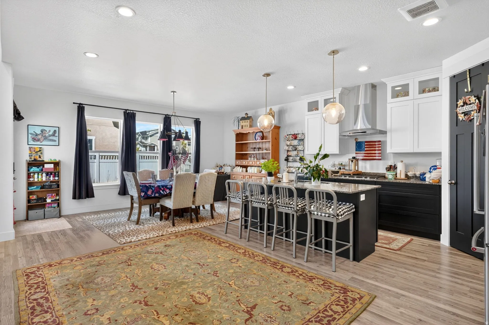 Open-concept living space featuring wood-finish flooring, recessed lighting, and a kitchen island with seating