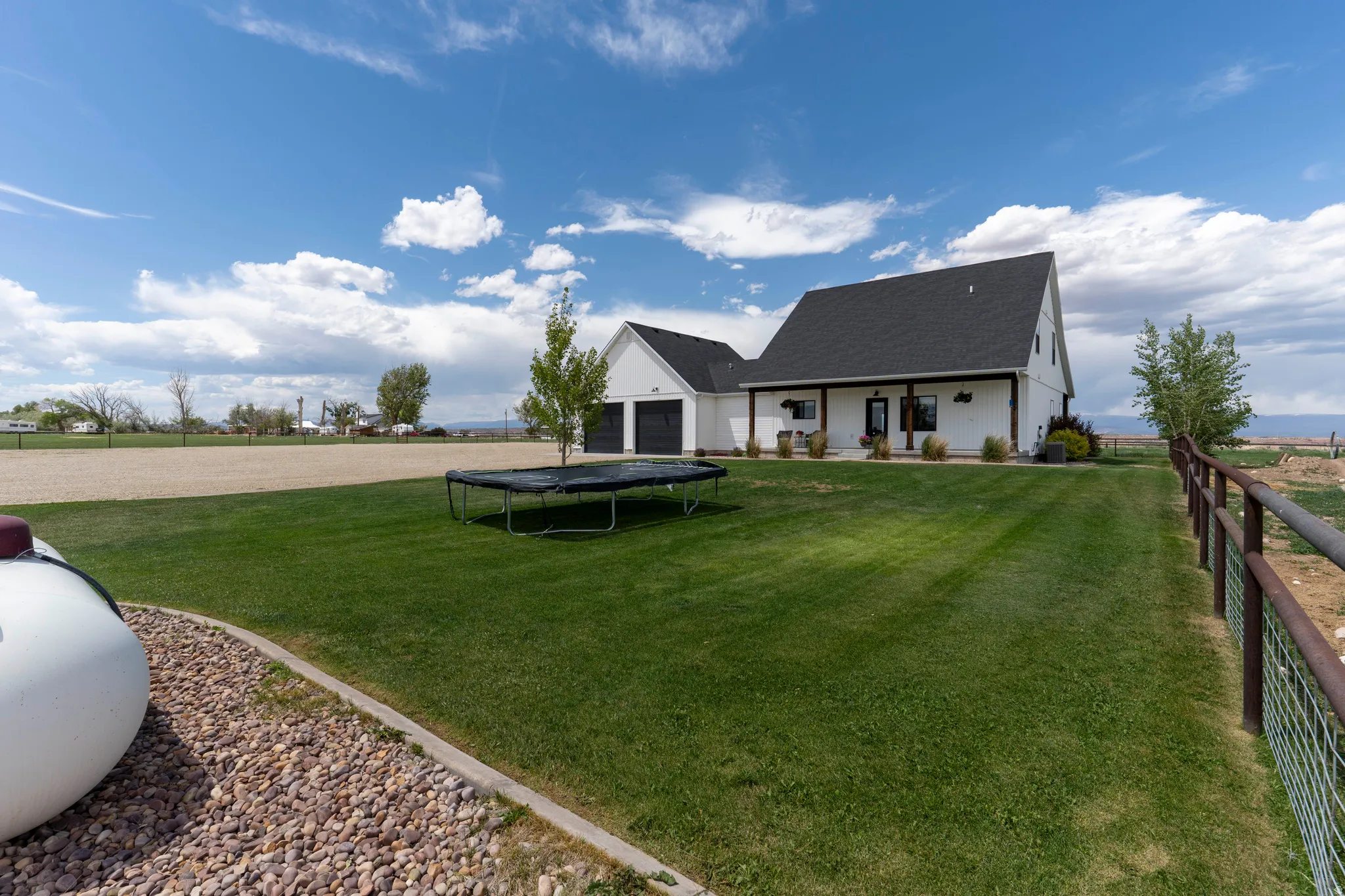 Spacious backyard featuring a manicured lawn, gravel border, and durable metal fencing