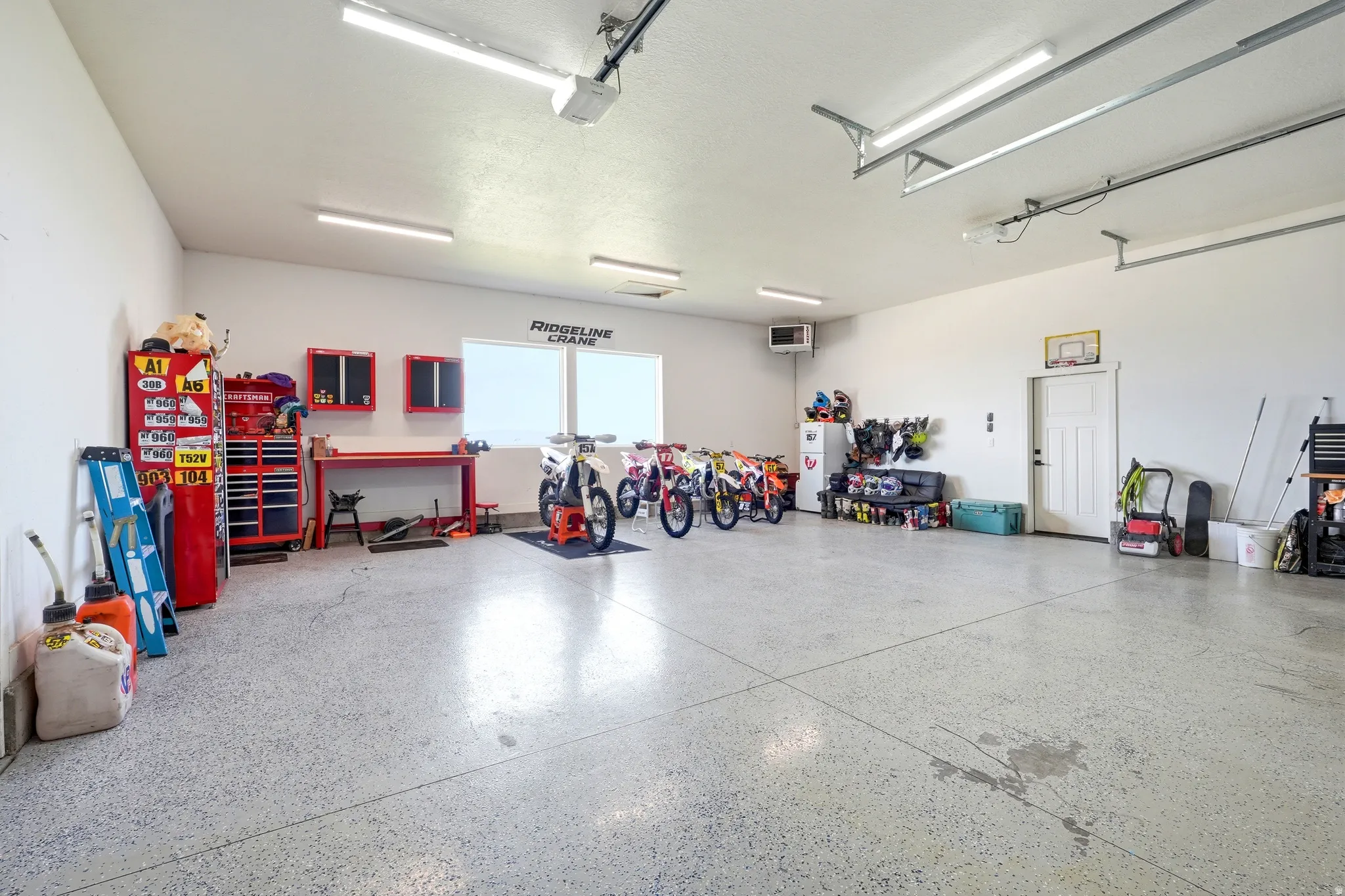 Spacious garage featuring an epoxy-coated concrete floor, bright overhead lighting, and abundant wall space