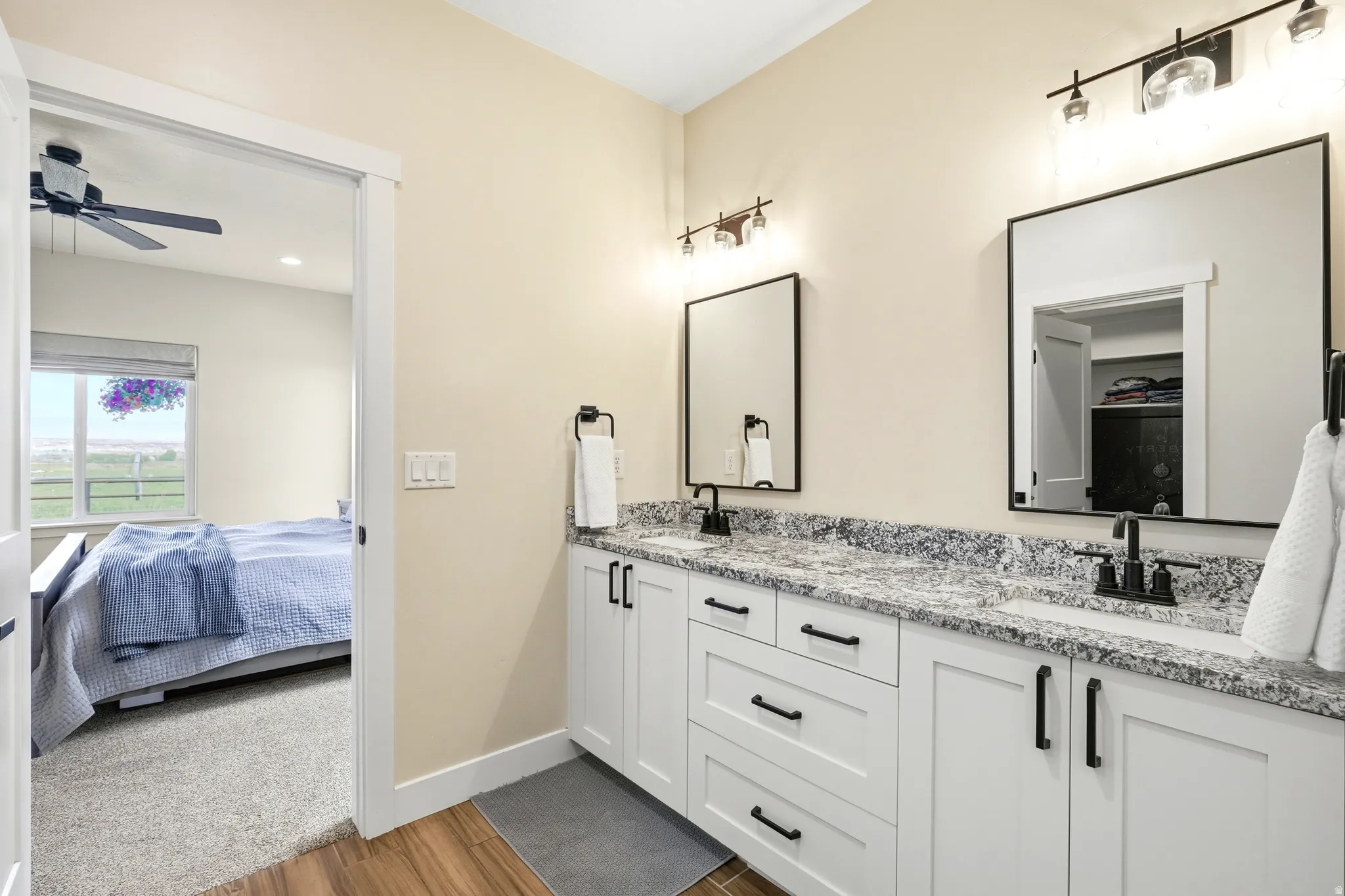 Dual vanity with white shaker cabinetry, black hardware, and speckled stone countertops
