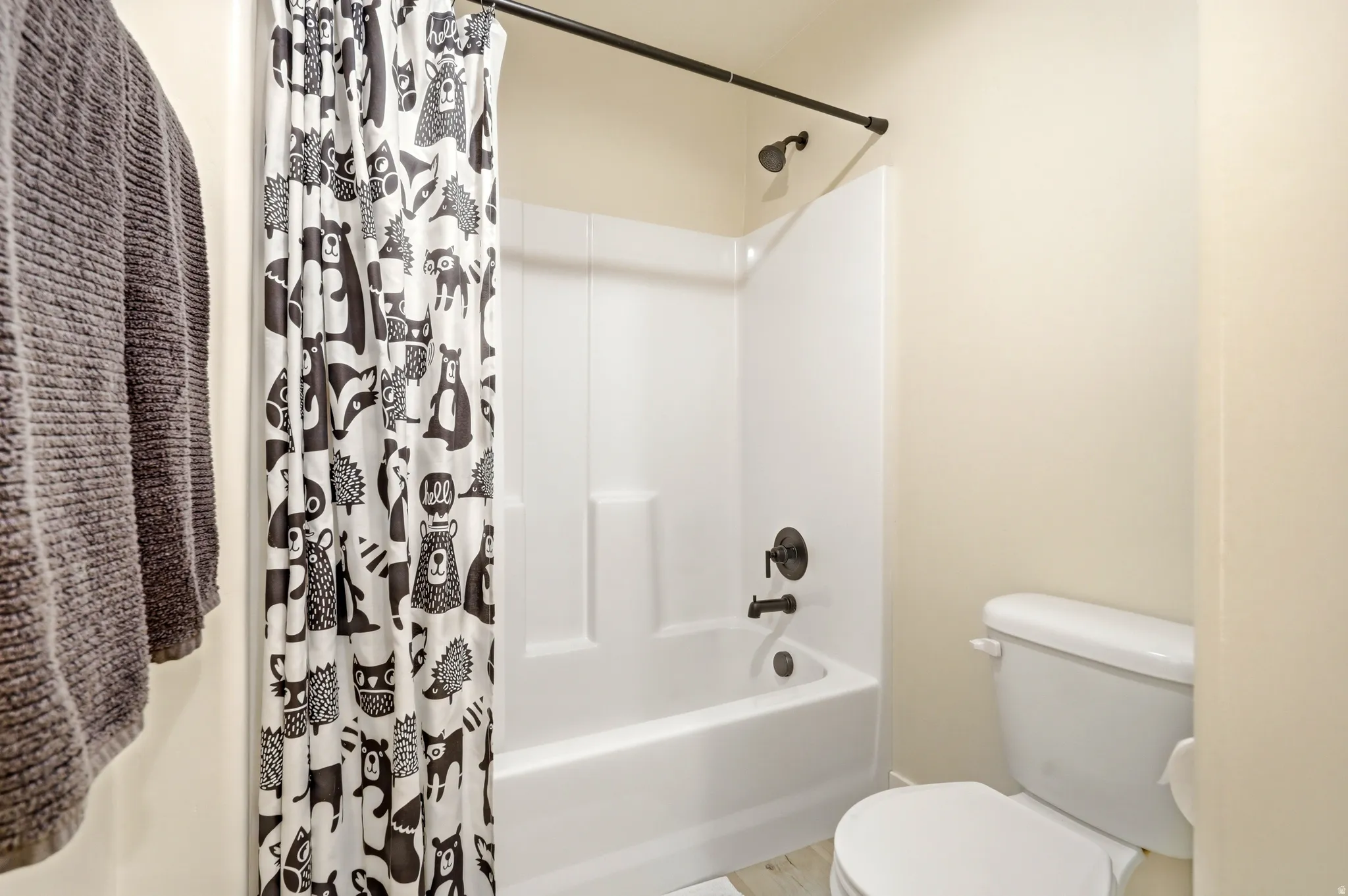 White acrylic bathtub and shower combination unit featuring dark bronze fixtures