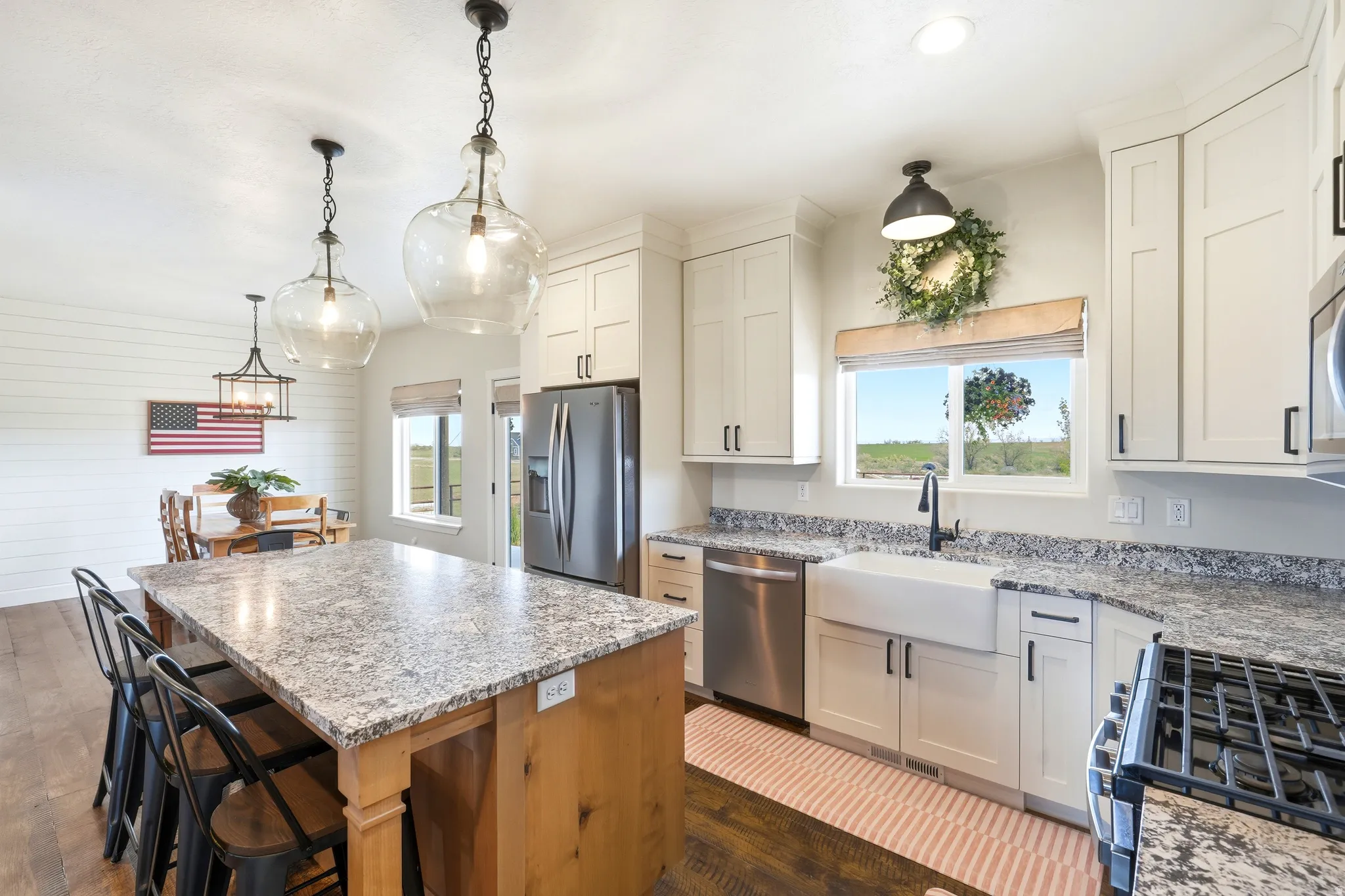 Well-appointed kitchen featuring light cabinetry, stainless steel appliances, a farmhouse sink, and a spacious island with counter seating
