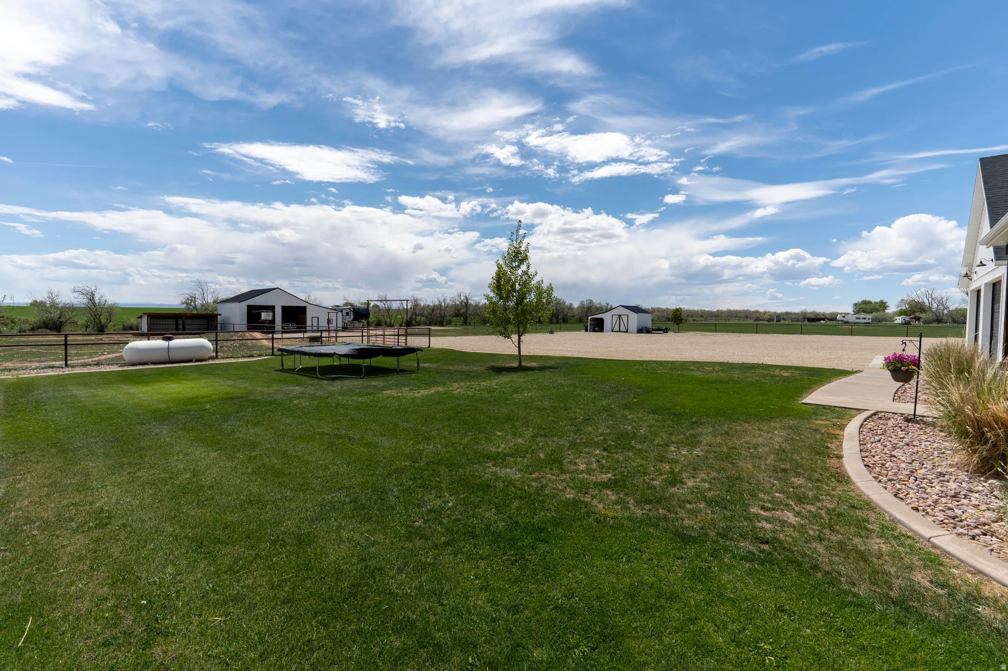 Expansive green lawn with a curved concrete pathway and decorative rock border