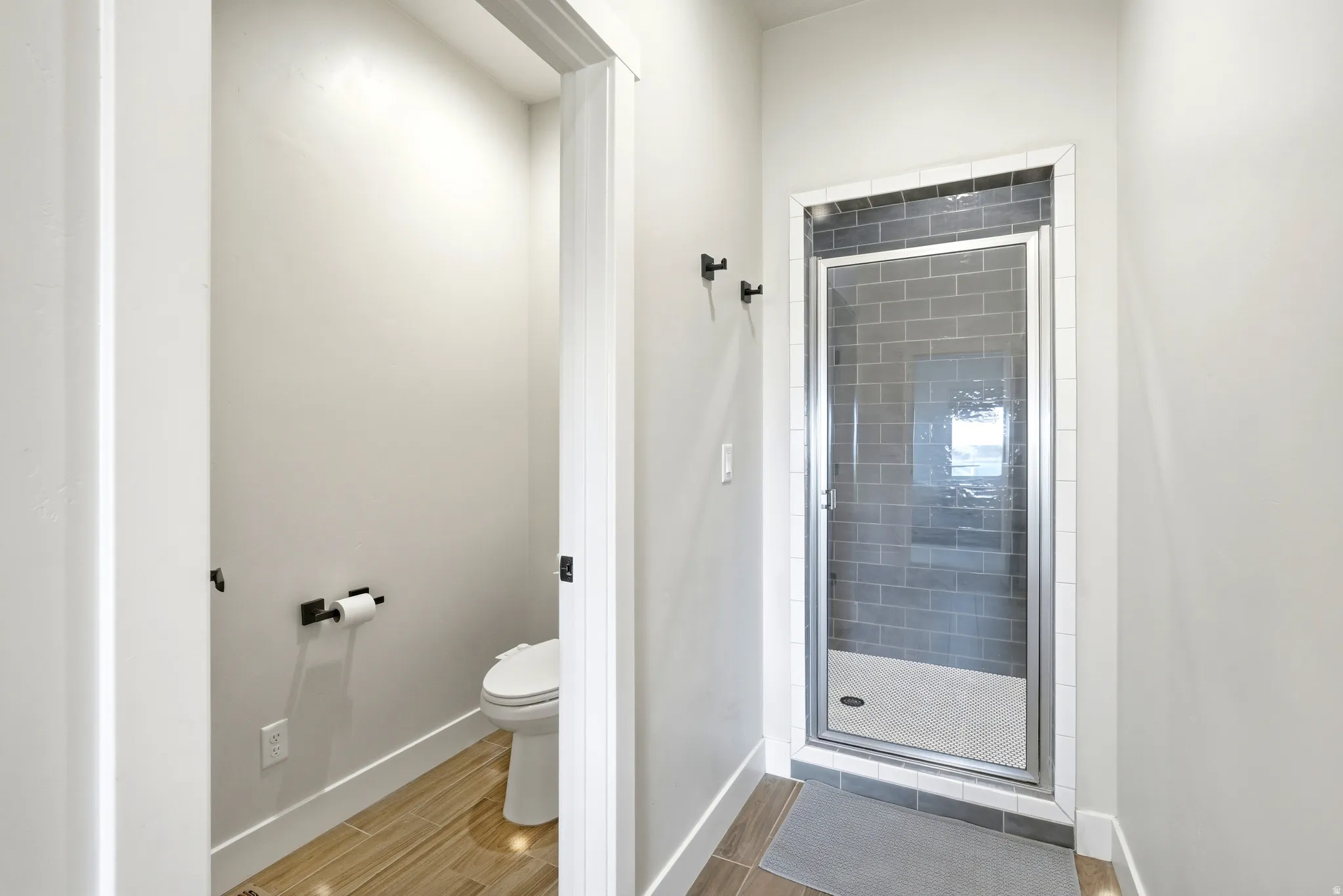 Contemporary shower enclosure with a glass door, dark gray subway tile surround, and light gray shower pan