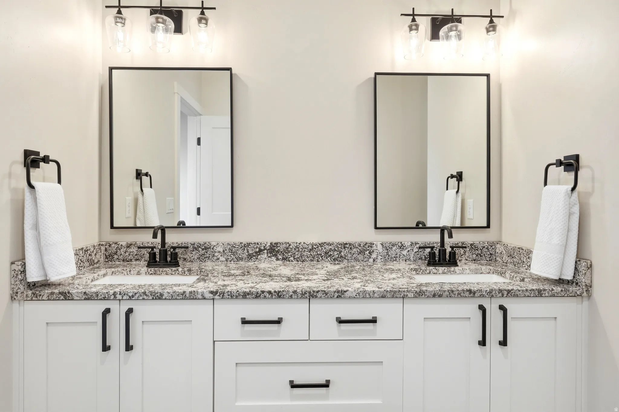 Dual vanity with white cabinetry, matte black hardware, integrated sinks