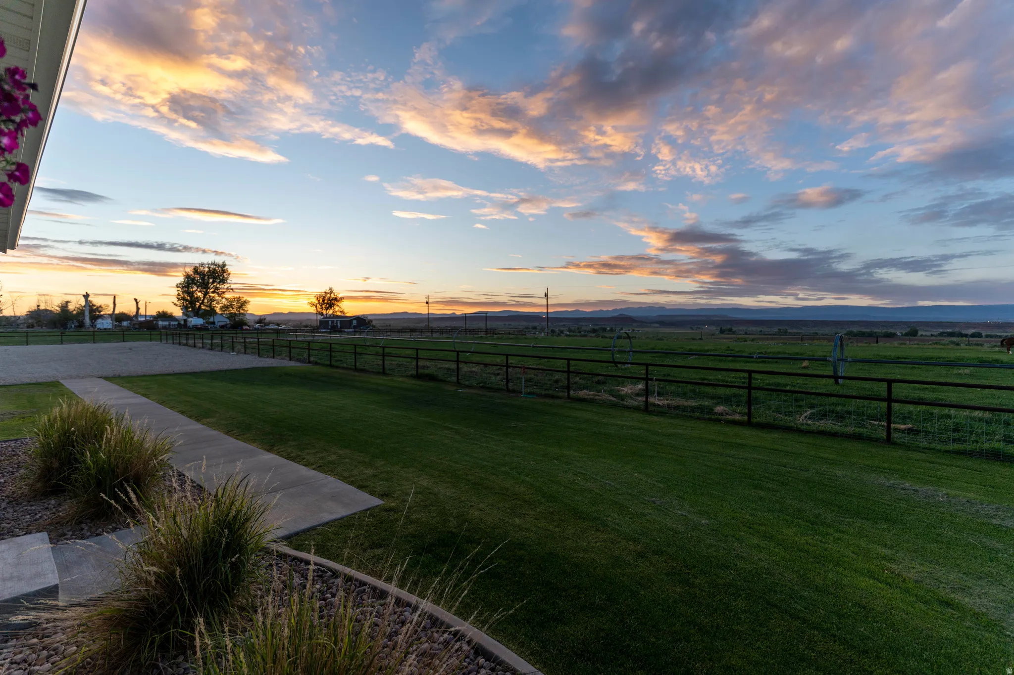 Expansive green lawn with a dark fence bordering a large field