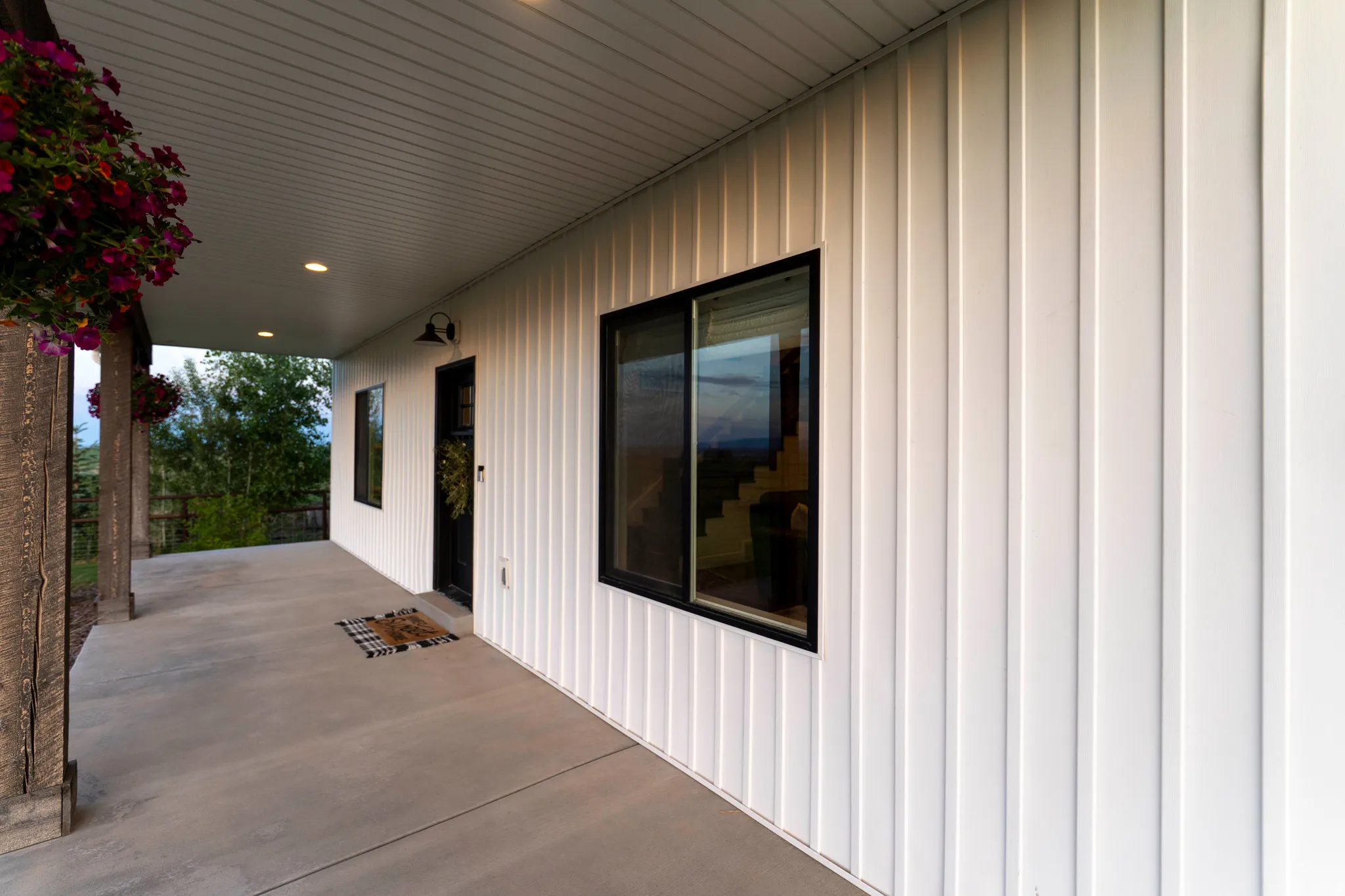 White vertical siding exterior with black-framed windows and a covered concrete porch