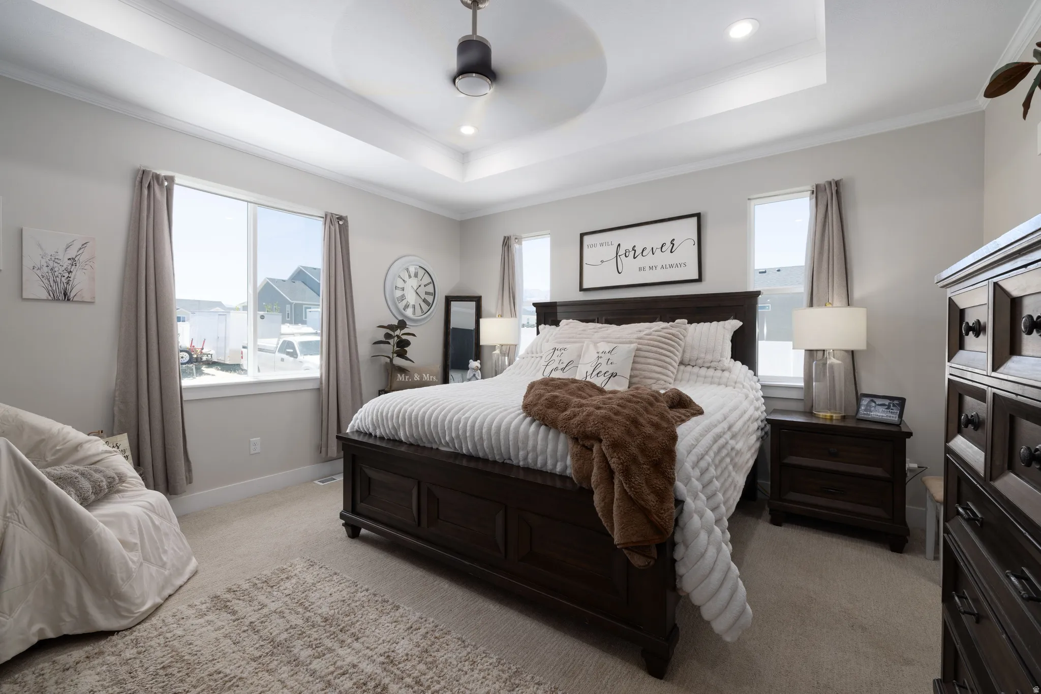 Primary Suite featuring light neutral wall paint, tray ceiling with a ceiling fan, recessed lighting, and carpet flooring