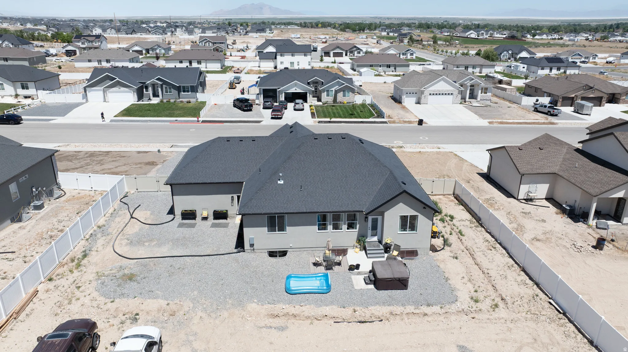 Rear property exterior featuring a multi-level patio area, a light gray stucco finish, and a dark shingle roof