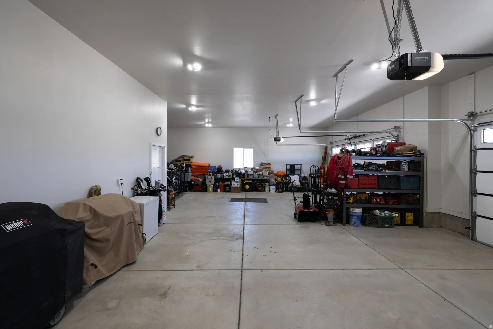 Expansive garage space featuring a concrete floor, multiple overhead garage doors with automatic openers, and recessed ceiling lighting
