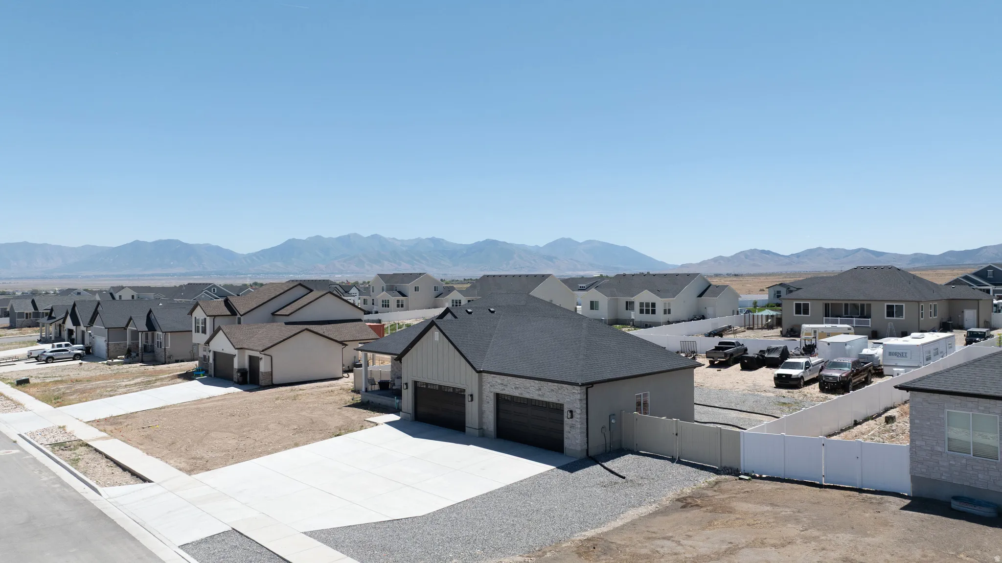 Modern ranch-style home featuring a two-car garage, dark asphalt shingle roof, light gray siding, and a concrete driveway