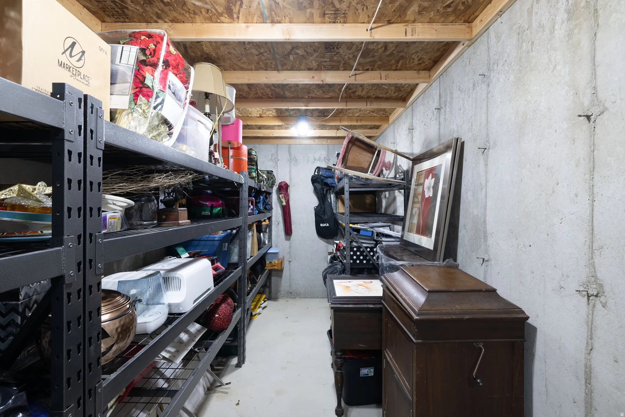 Unfinished basement space featuring exposed wood joists and concrete walls, with ample room for storage or future development