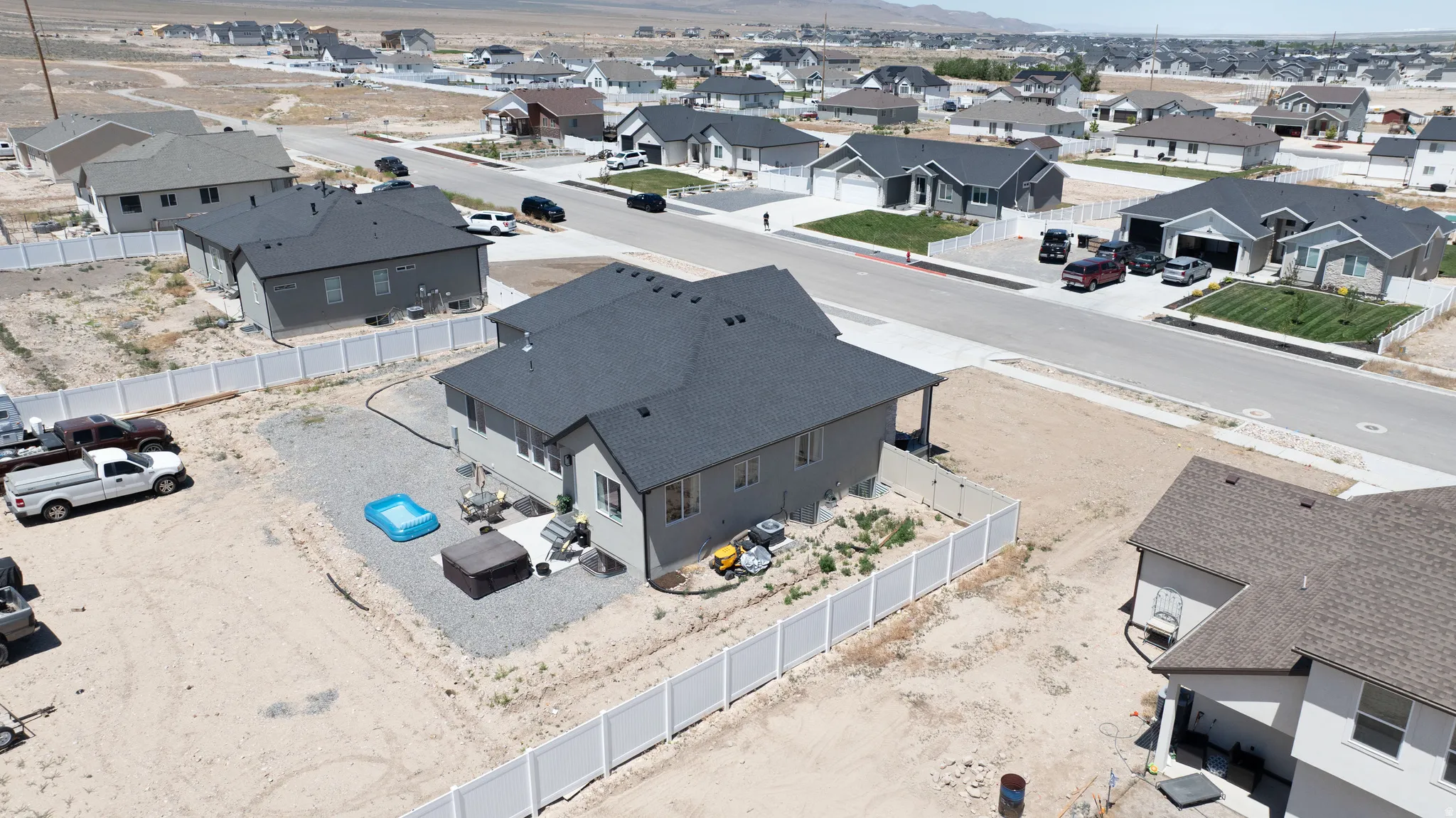 Aerial perspective of a contemporary residential property featuring a dark shingle roof and light gray siding