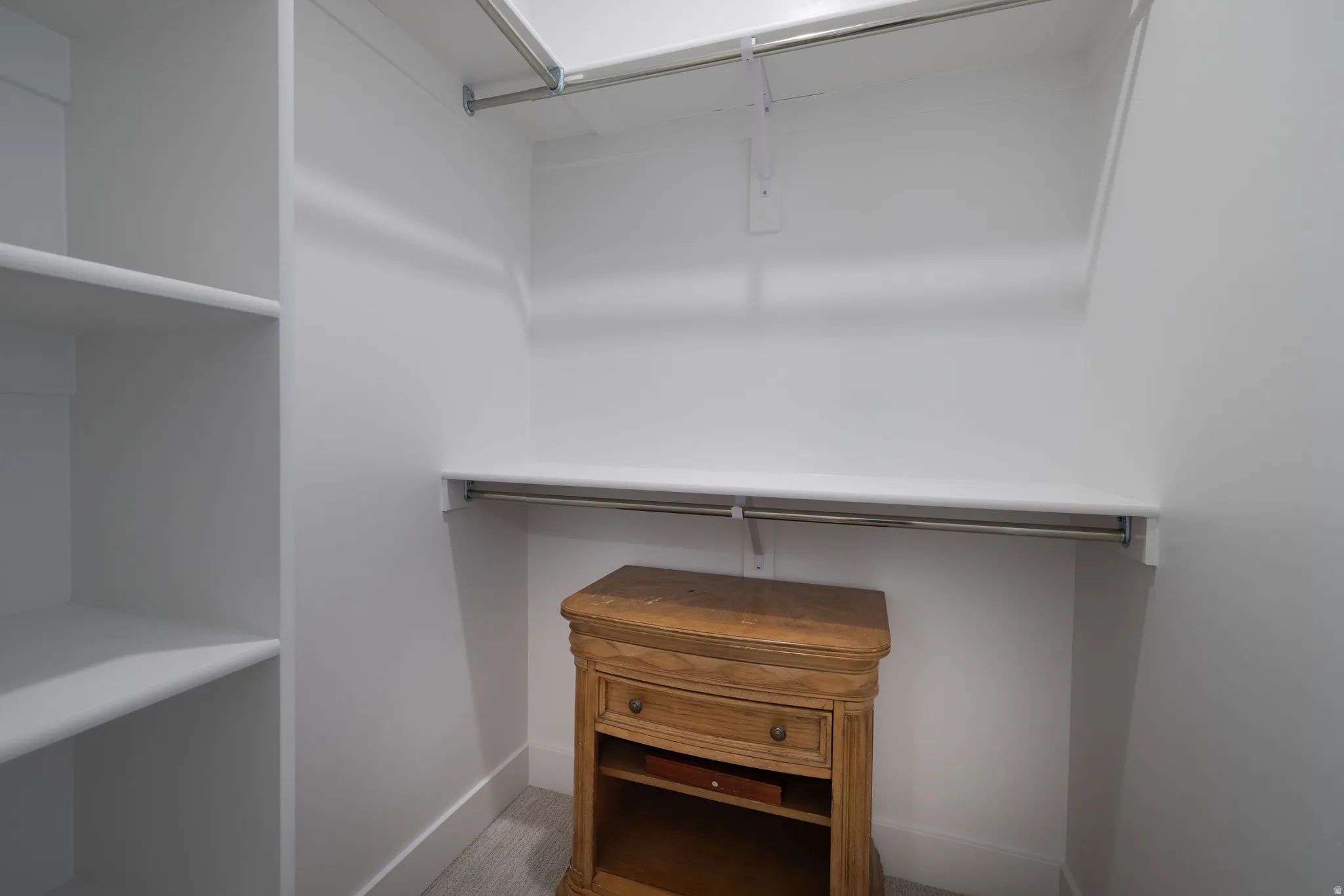 Custom closet system with built-in shelving and dual hanging rods, featuring white finished walls and baseboards