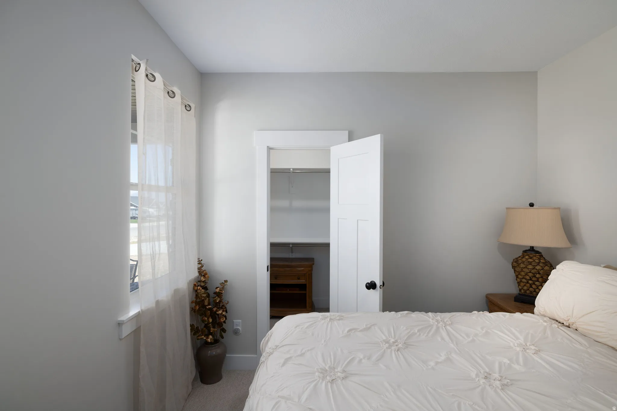 Bedroom featuring neutral wall colors, carpeted flooring, a panel door, and an open closet with built-in shelving