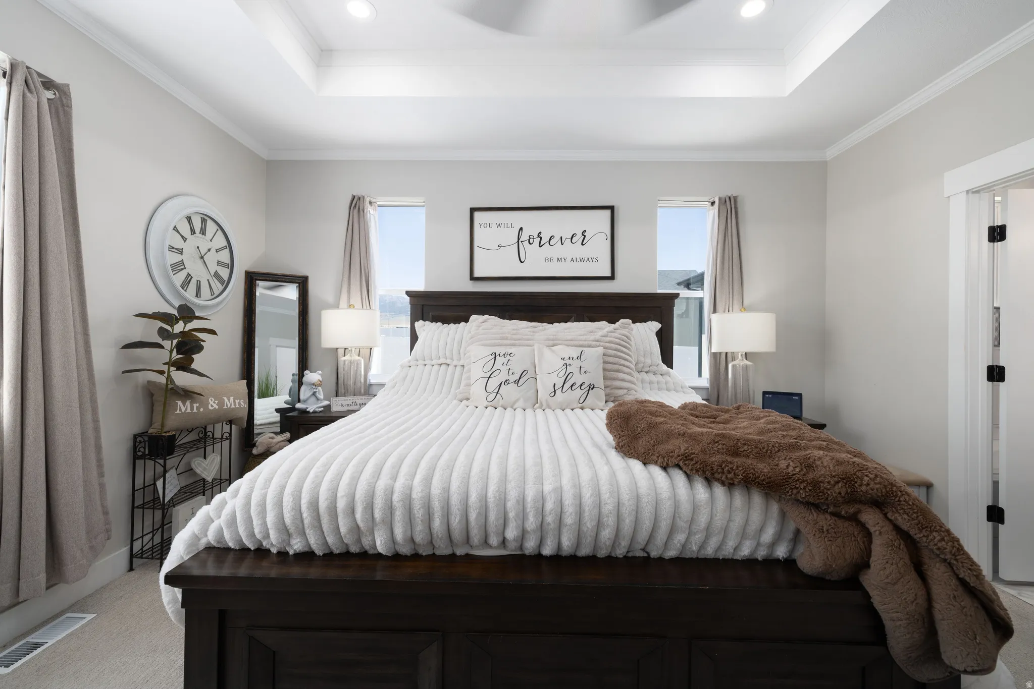 Primary Suite featuring a tray ceiling with recessed lighting and a ceiling fan, light gray wall paint, and two windows with curtains