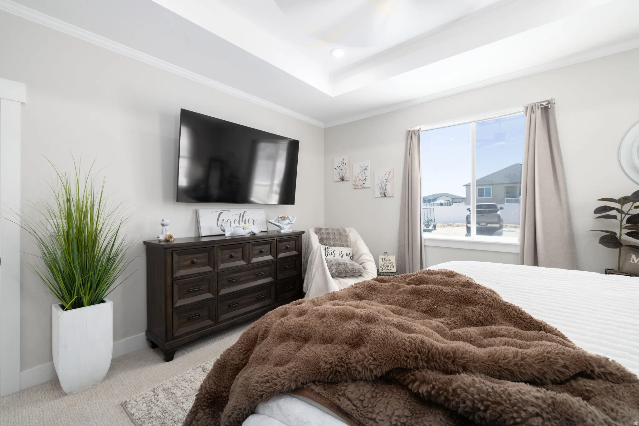 Tray ceiling with crown molding, light neutral wall paint, and a large window with neutral drapery