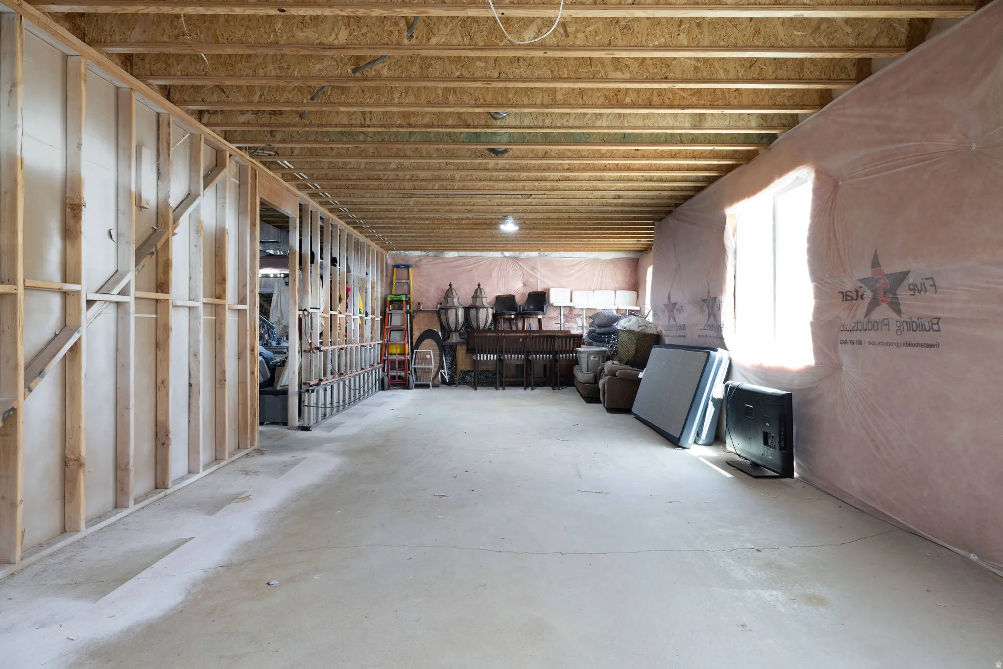 Unfinished basement with exposed wood joists and concrete flooring