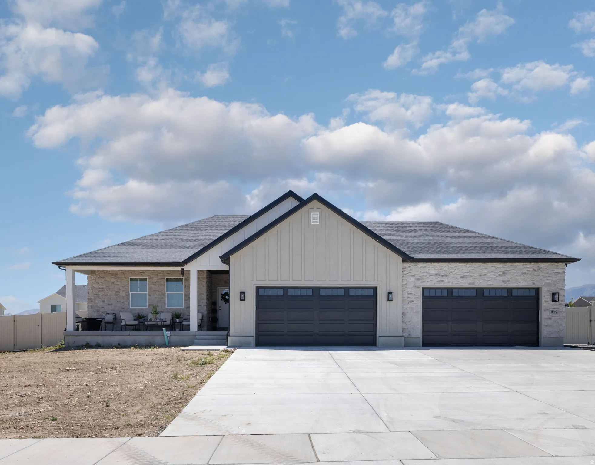 Modern ranch-style home featuring a covered front porch, and a 4-car garage