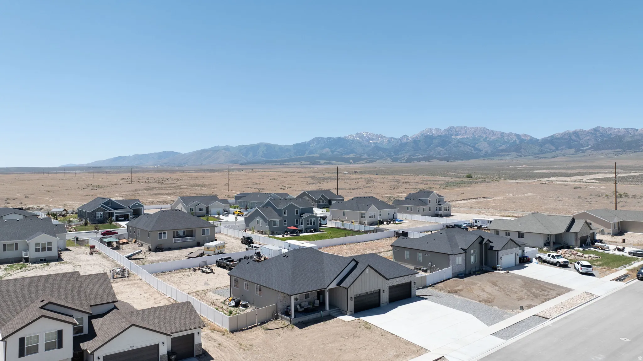 Expansive neighborhood featuring single-story and two-story homes with attached garages, concrete driveways, and white fencing