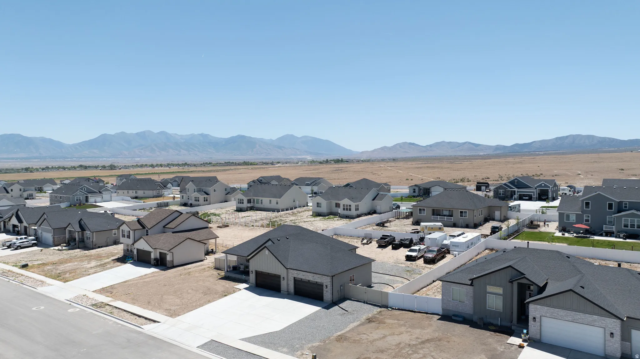 Aerial perspective showcasing a residential community with contemporary homes, mountain backdrop, and expansive open land