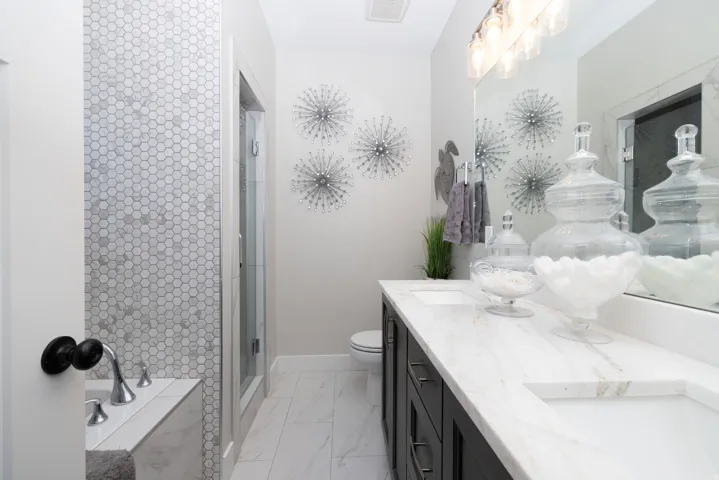 Primary Suite featuring a double vanity with granite countertops, integrated rectangular sinks, and dark wood-finish cabinetry