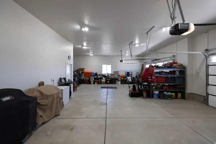 Expansive garage space featuring a concrete floor, multiple overhead garage doors with automatic openers, and recessed ceiling lighting