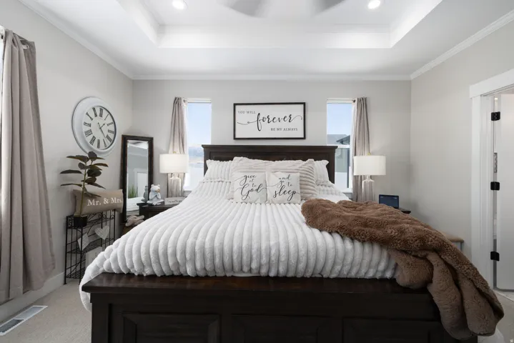 Primary Suite featuring a tray ceiling with recessed lighting and a ceiling fan, light gray wall paint, and two windows with curtains