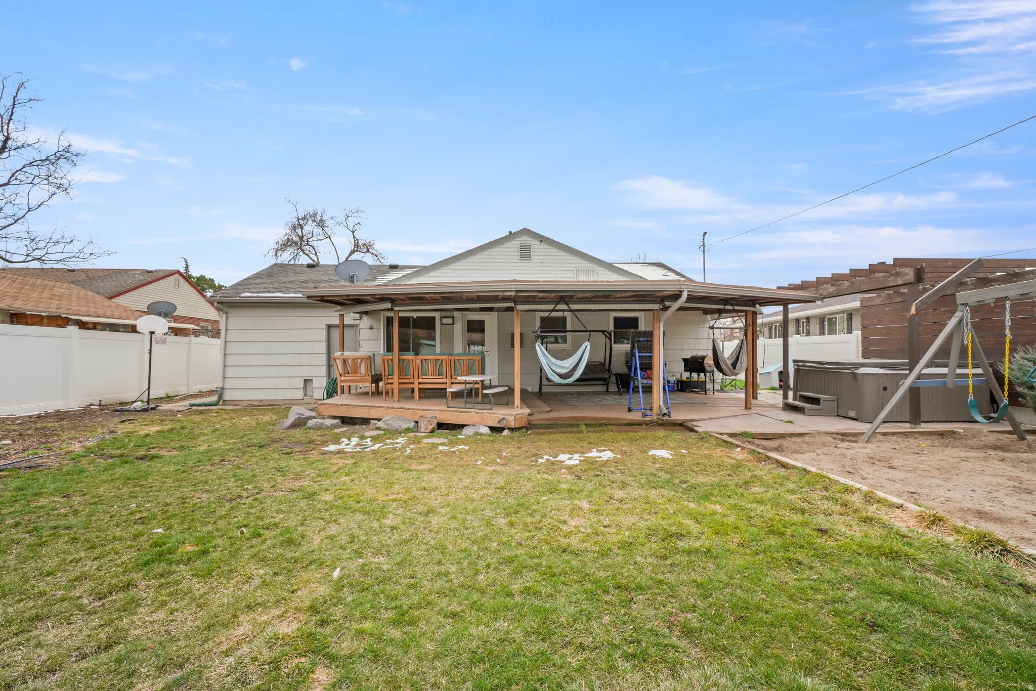 Rear exterior featuring a covered patio with a wood deck extension, sliding glass door access, and a concrete patio section