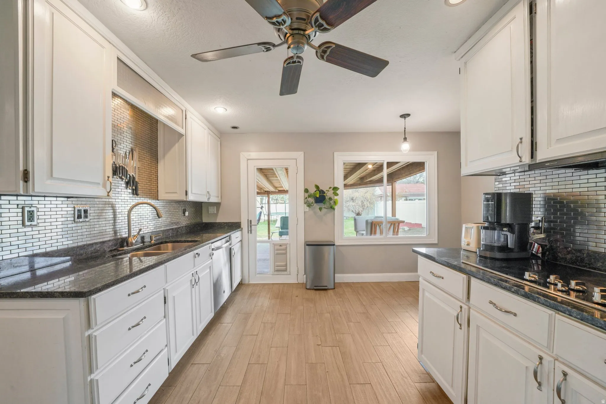 Kitchen featuring white cabinetry, dark stone-finish countertops, and a full tile backsplash