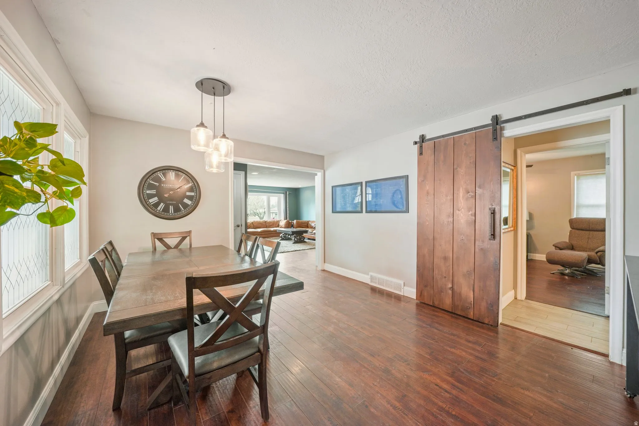 Dining area featuring wood-finish flooring, a modern pendant light fixture, and a sliding barn door with dark hardware