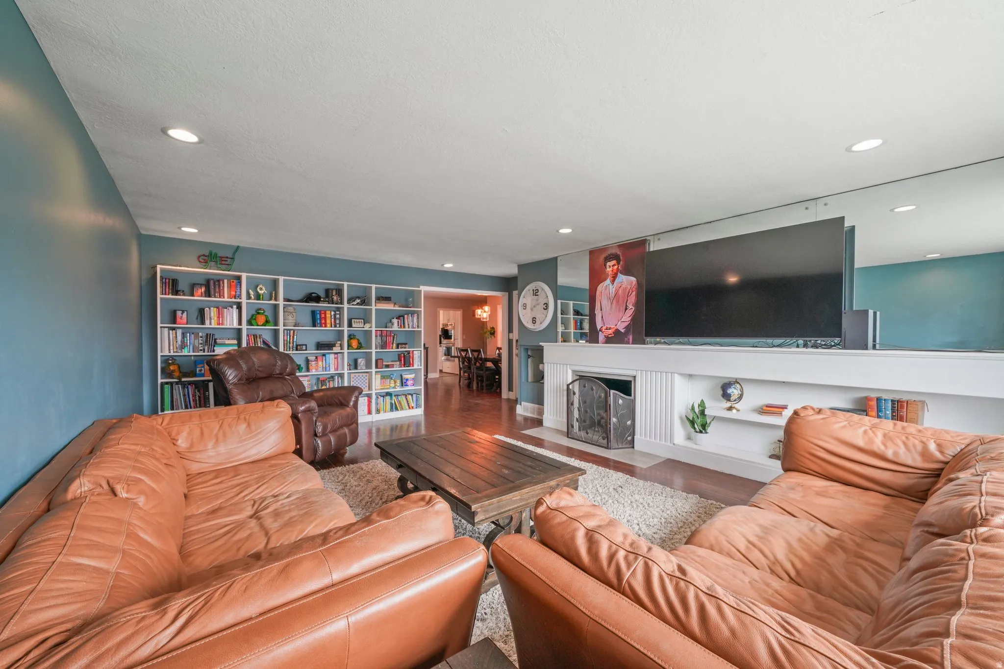 Open-concept living area featuring a built-in fireplace with decorative screen, recessed lighting, and wood-finish flooring