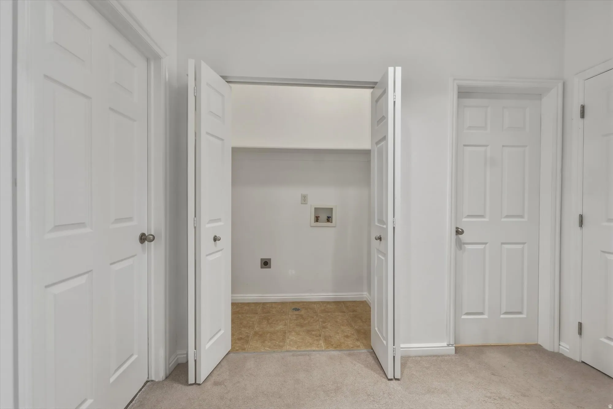 Dedicated laundry alcove with bi-fold doors, utility hookups, and durable flooring
