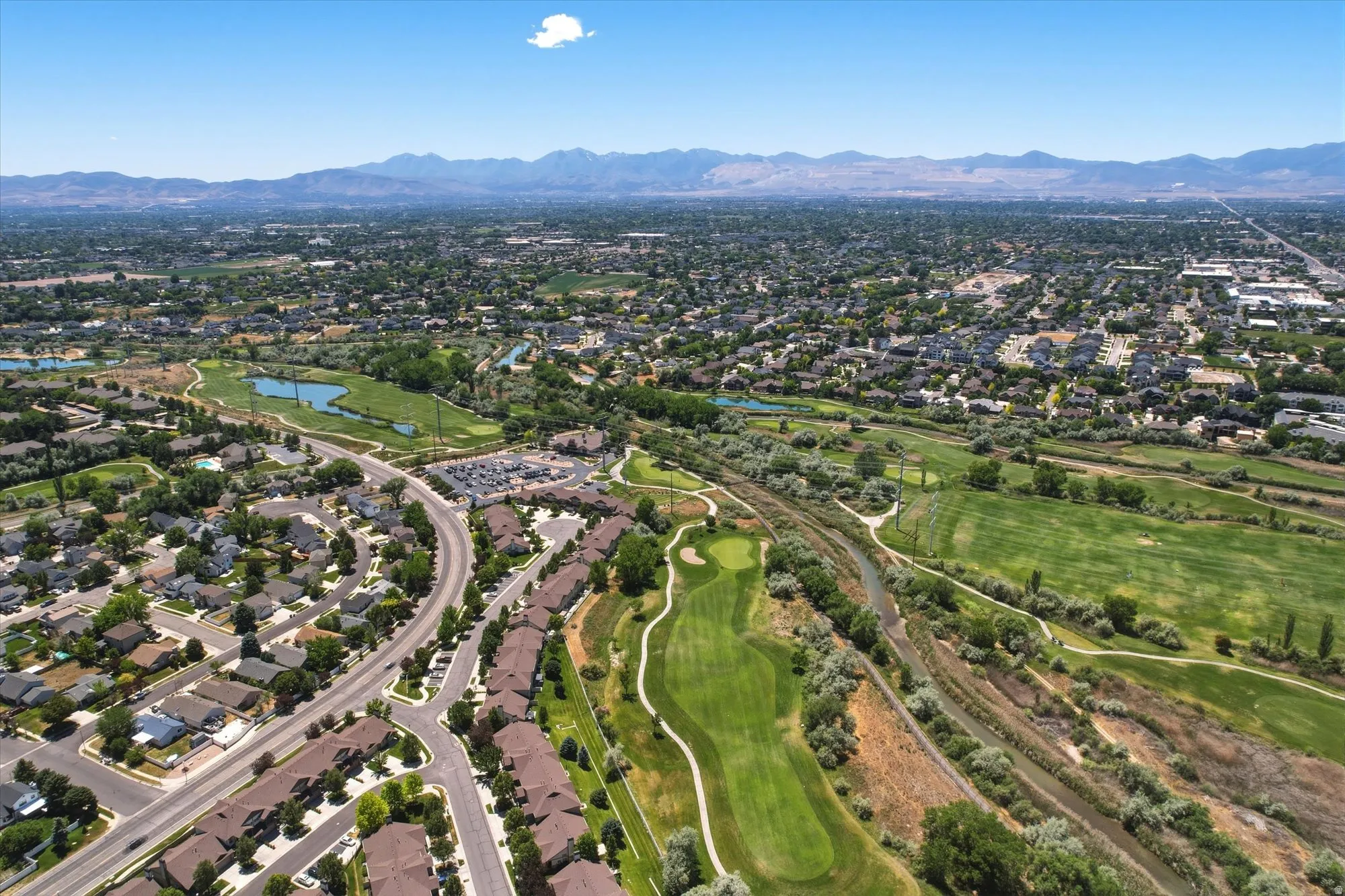 Aerial perspective showcasing a residential area with varied housing styles, bordered by extensive green spaces and a golf course