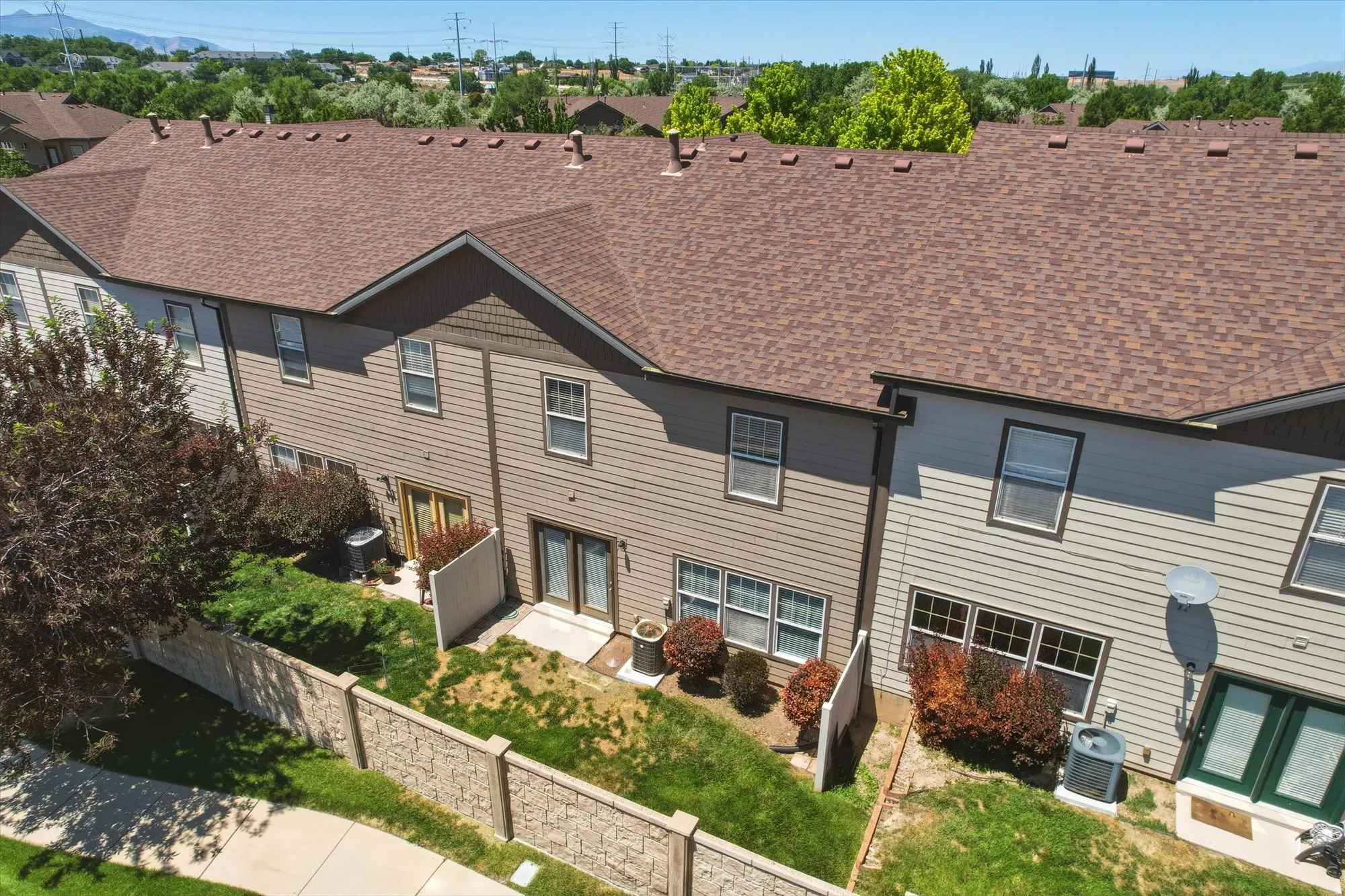 Townhome exteriors featuring horizontal siding, gabled rooflines with asphalt shingles, and ground-level patios with double-door access