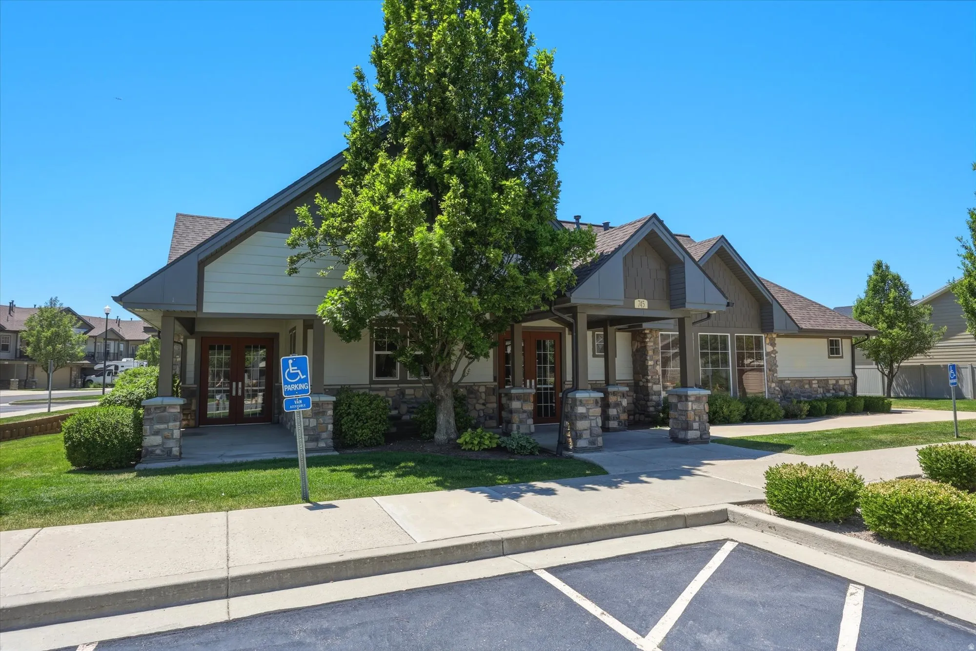 Exterior building featuring a gabled roofline, stone veneer accents, and multiple entryways with double glass doors